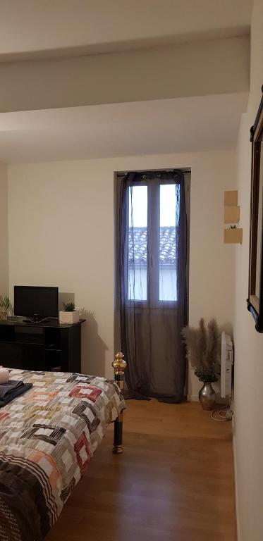a bedroom with a bed and a window and a desk at Exotik in Graulhet