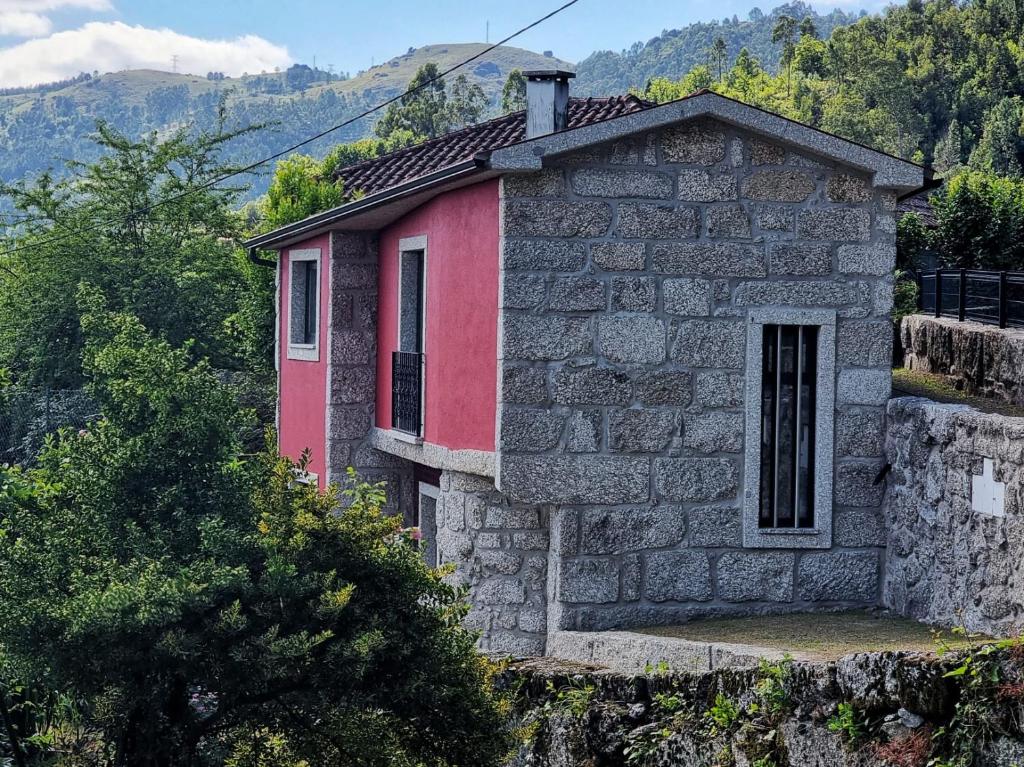 a small stone house with a red front at Casinha da Mó in Vieira do Minho