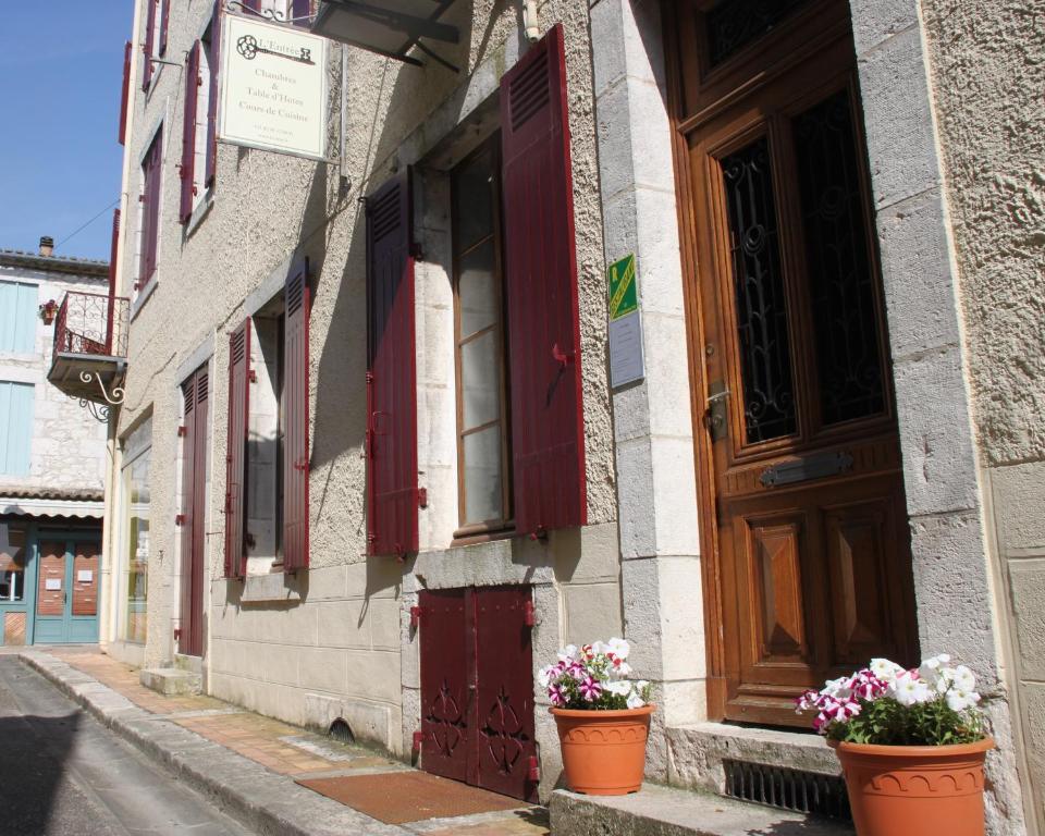 un bâtiment avec deux pots de fleurs devant une porte dans l'établissement L'Entrée Chambres d'Hôtes Bar & Restaurant, à Castillonnès