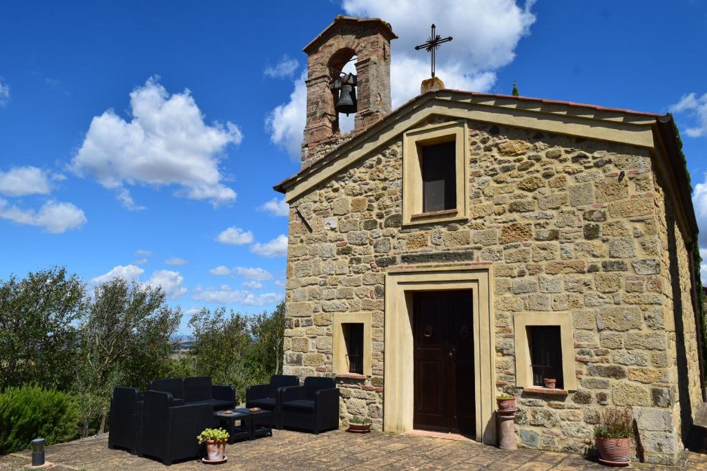 eine alte Steinkirche mit einem Kreuz darüber in der Unterkunft Villa San Sebastiano Montalcino in Montalcino