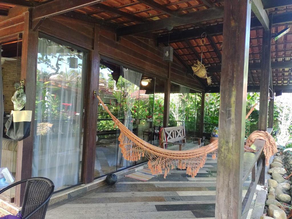 eine Hängematte auf der Veranda eines Hauses in der Unterkunft Charmosa casa com churrasq na praia de Camburi in São Sebastião