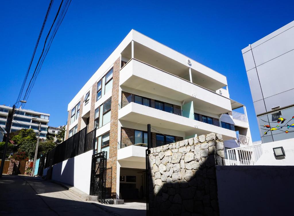 a white apartment building with a stone wall at Departamentos Vellemar Reñaca in Viña del Mar