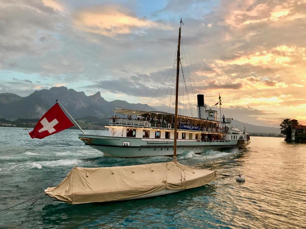 ein Boot mit einer Schaukelflagge im Wasser in der Unterkunft Chalet Oberhofen am Thunersee in Oberhofen am Thunersee