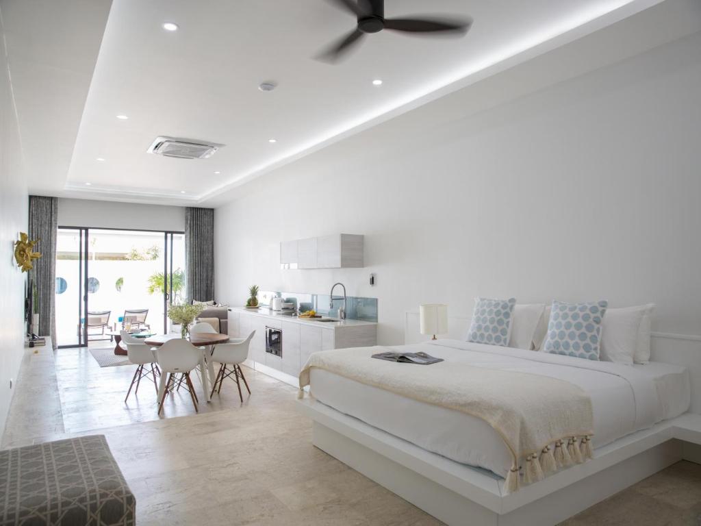 a white bedroom with a large bed and a kitchen at Skye Beach Hotel - Koh Samui in Choeng Mon Beach