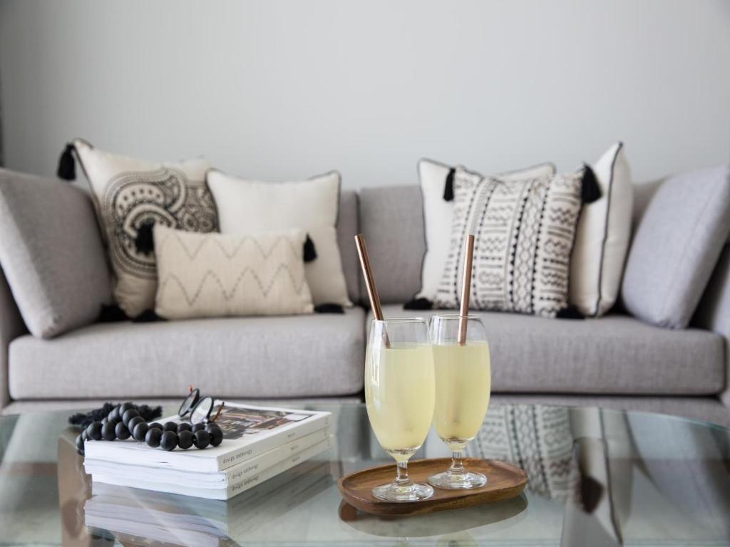 a living room with a couch and two drinks on a glass table at Skye Beach Hotel - Koh Samui in Choeng Mon Beach