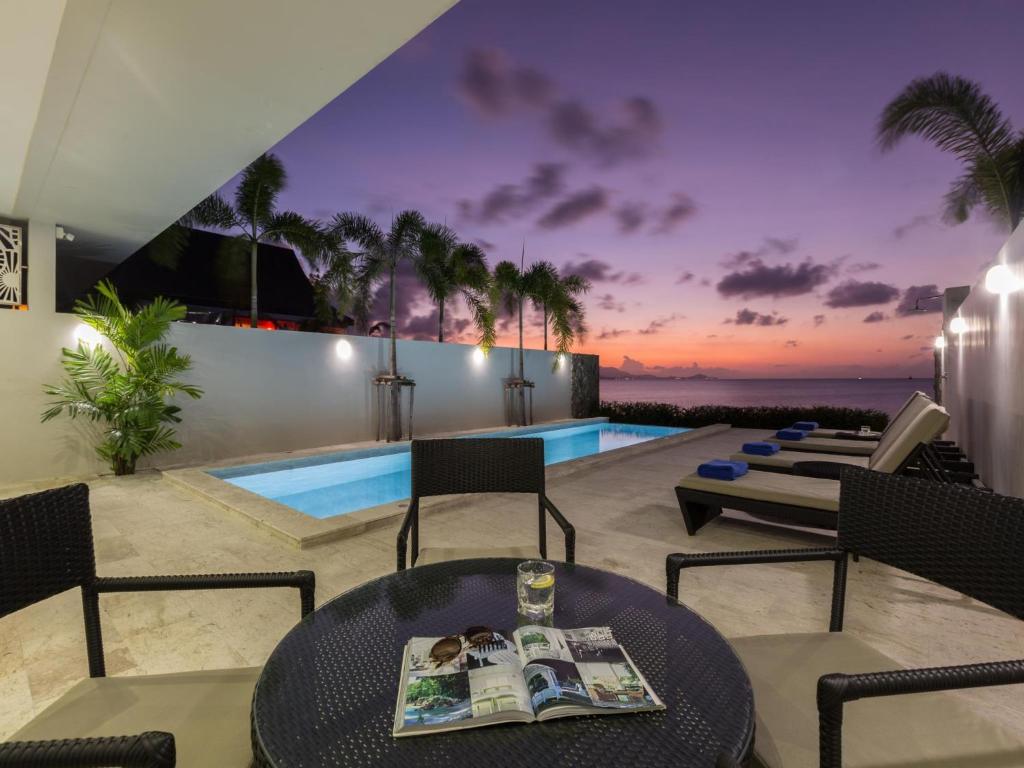 a living room with a table and chairs and a swimming pool at Skye Beach Hotel - Koh Samui in Choeng Mon Beach