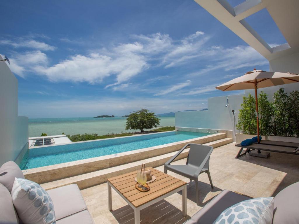 a villa with a swimming pool with a table and an umbrella at Skye Beach Hotel - Koh Samui in Choeng Mon Beach