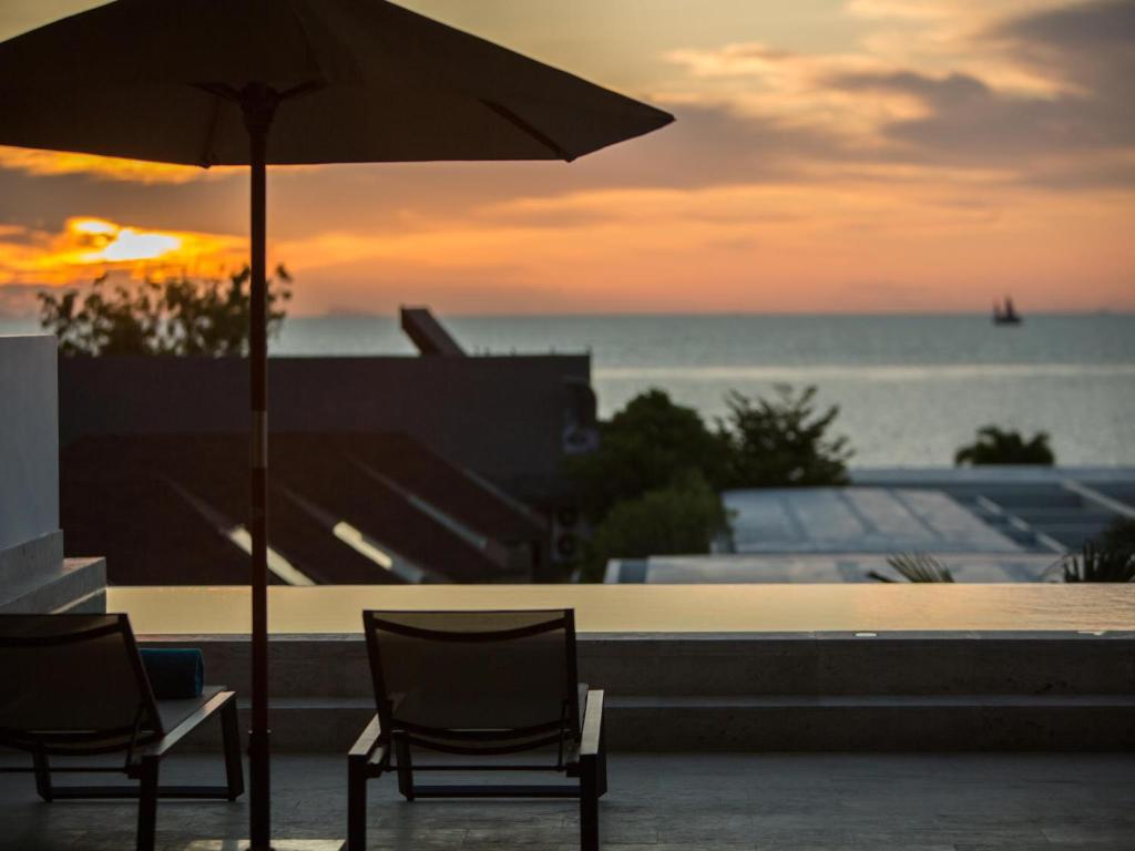 two chairs and an umbrella in front of the ocean at Skye Beach Hotel - Koh Samui in Choeng Mon Beach