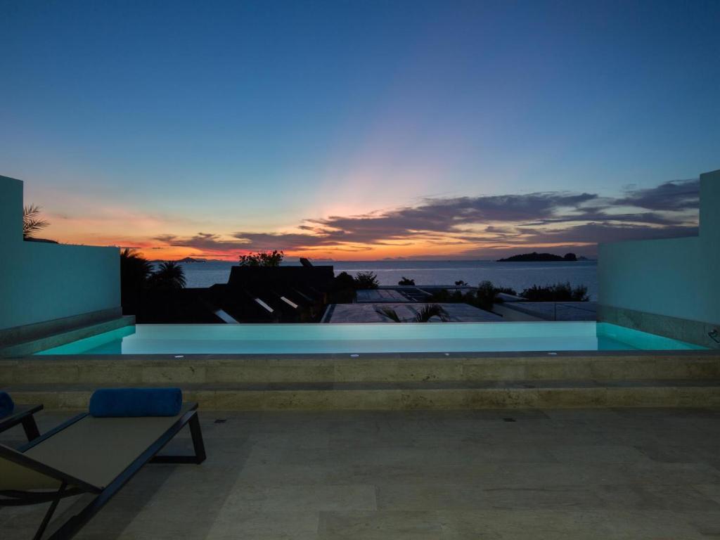a swimming pool with a sunset in the background at Skye Beach Hotel - Koh Samui in Choeng Mon Beach