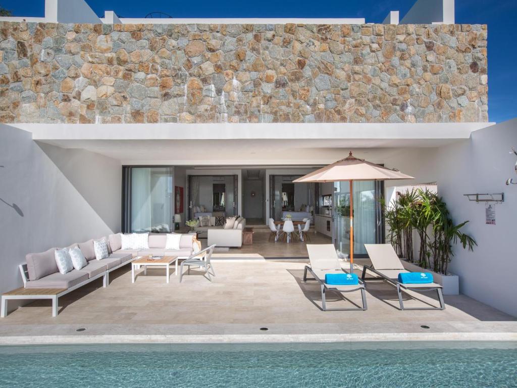 an outdoor patio with chairs and an umbrella and a pool at Skye Beach Hotel - Koh Samui in Choeng Mon Beach