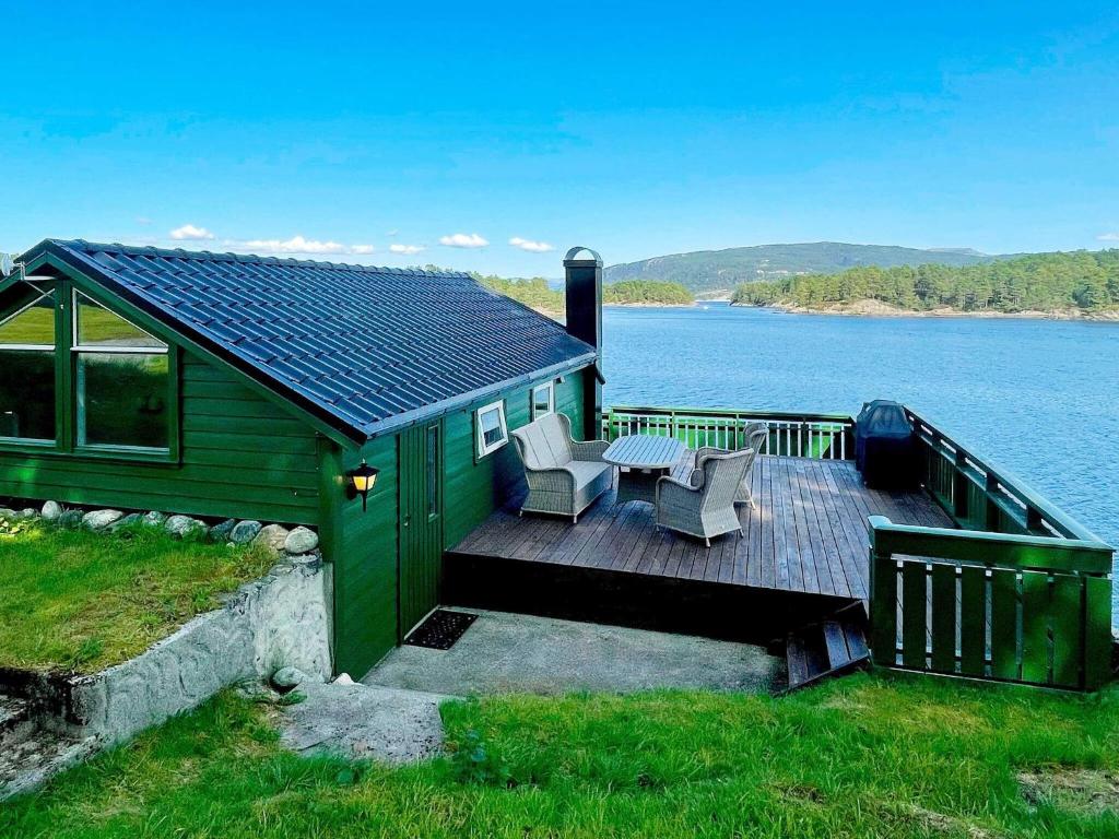 eine grüne Hütte mit einem Tisch und Stühlen auf einer Terrasse in der Unterkunft Holiday home LINDÅS in Lindås