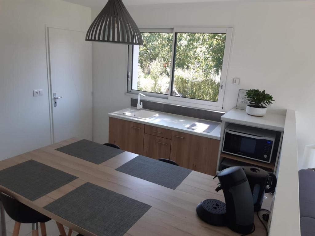 cocina con mesa de madera y ventana en Maison entre Mer et Brière. Proche de La Baule et de Guérande. en Saint-André-des-Eaux