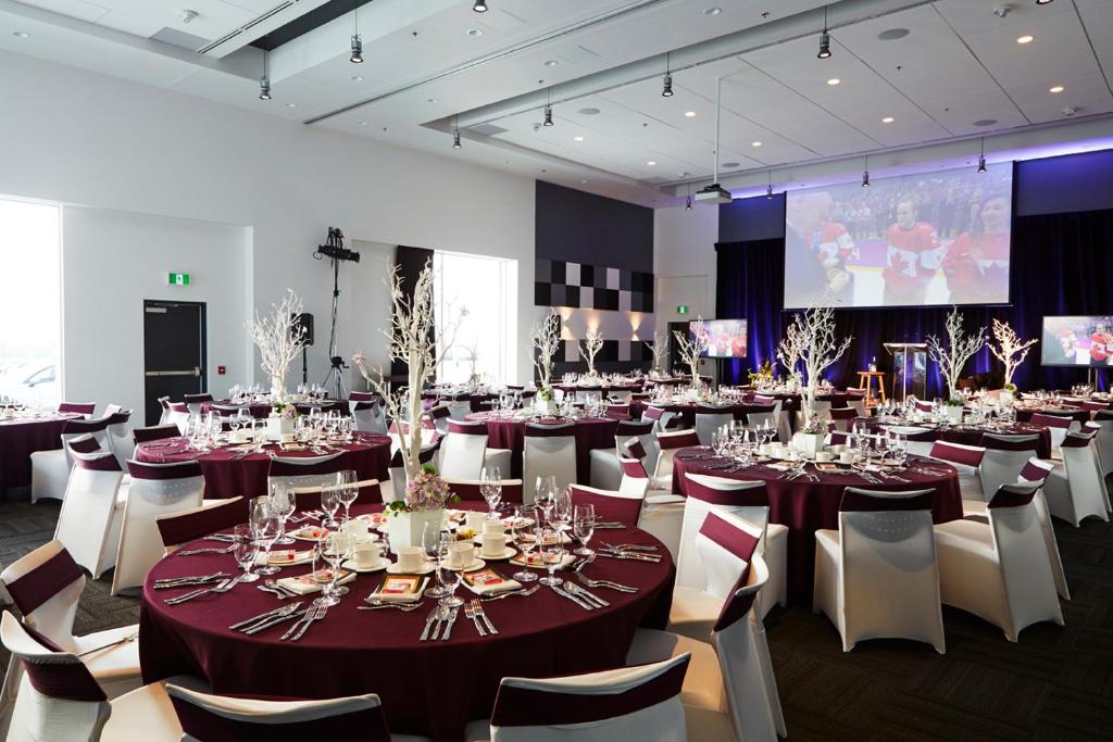 a banquet hall with tables and chairs and a screen at Alt Hotel Halifax Airport in Enfield