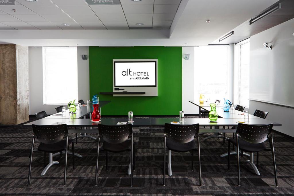 a conference room with a green wall and tables and chairs at Alt Hotel Halifax Airport in Enfield