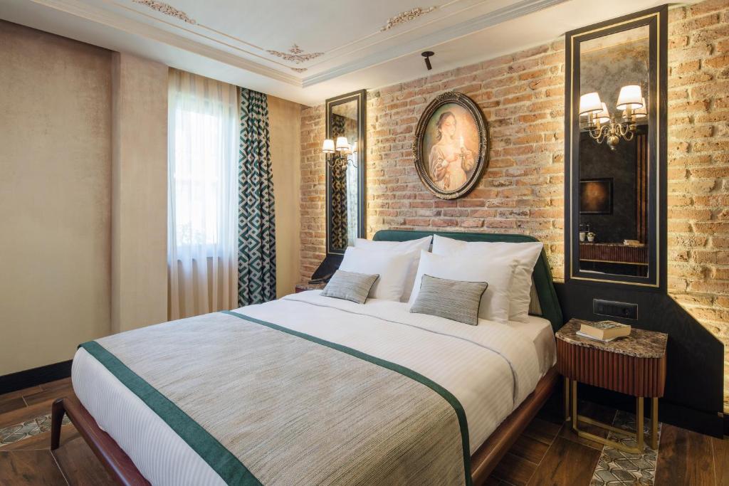 イスタンブールにあるトリア ホテル イスタンブールのレンガの壁、大きなベッド付きのベッドルーム1室