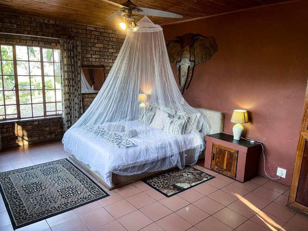 a bedroom with a bed with a mosquito net at Masasana’s Rest in Hazyview