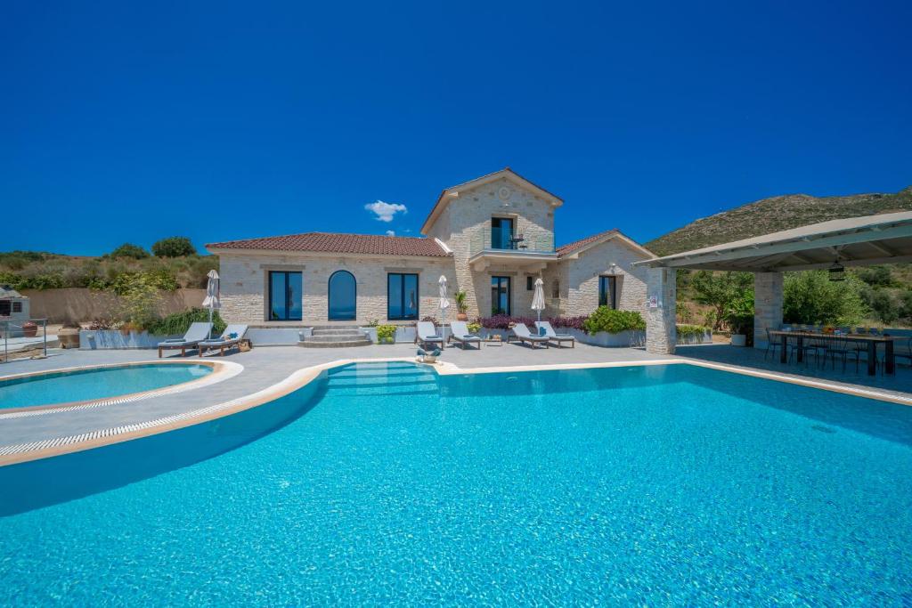 a large swimming pool in front of a house at Kaminia Blu in Ratzaklíon