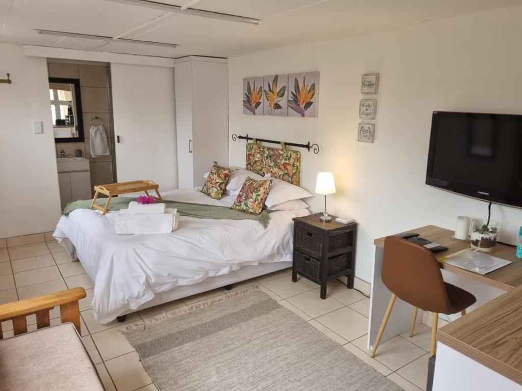 ein Wohnzimmer mit einem Bett und einem TV in der Unterkunft Impunzi Place in Kloof
