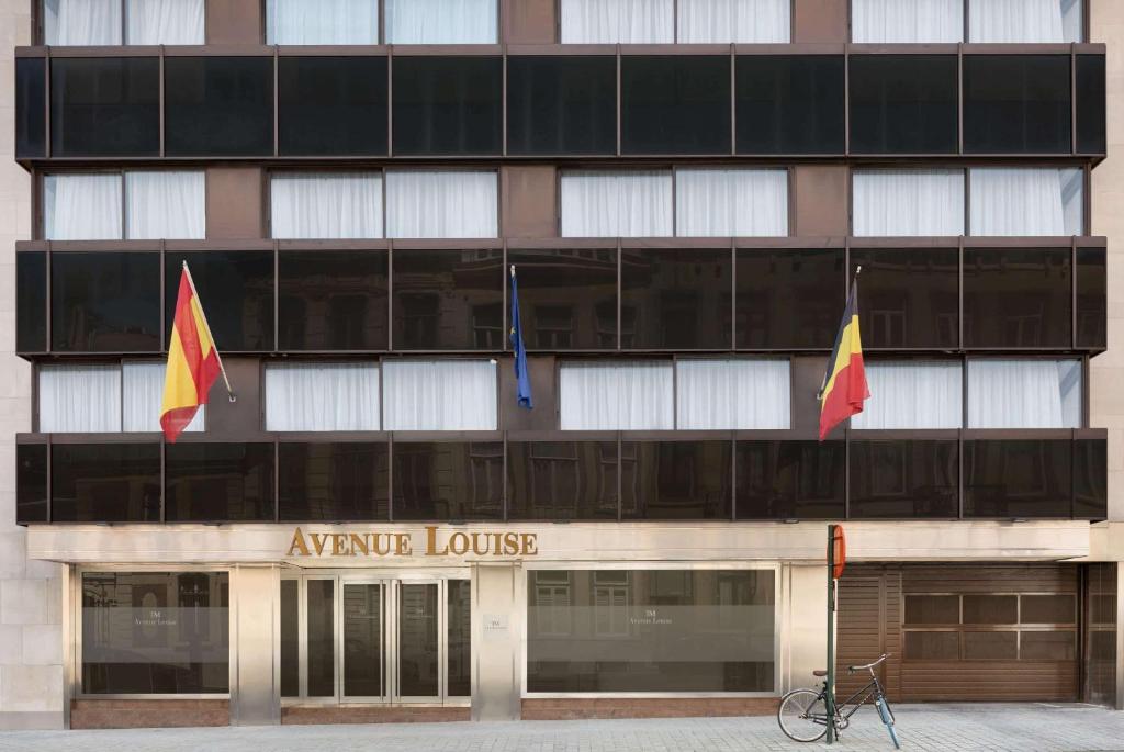 ein Gebäude mit zwei Flaggen davor in der Unterkunft Hotel Avenue Louise Brussels Trademark Collection by Wyndham in Brüssel