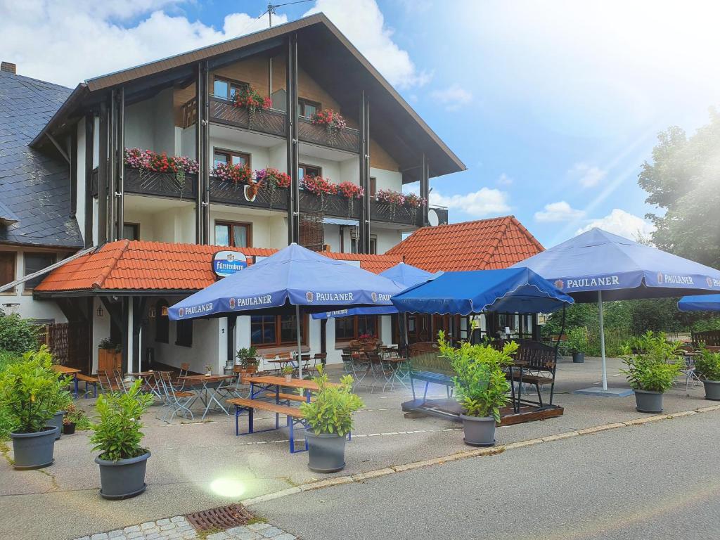 a hotel with tables and blue umbrellas in front of it at Landgasthof Ritter in Villingen-Schwenningen