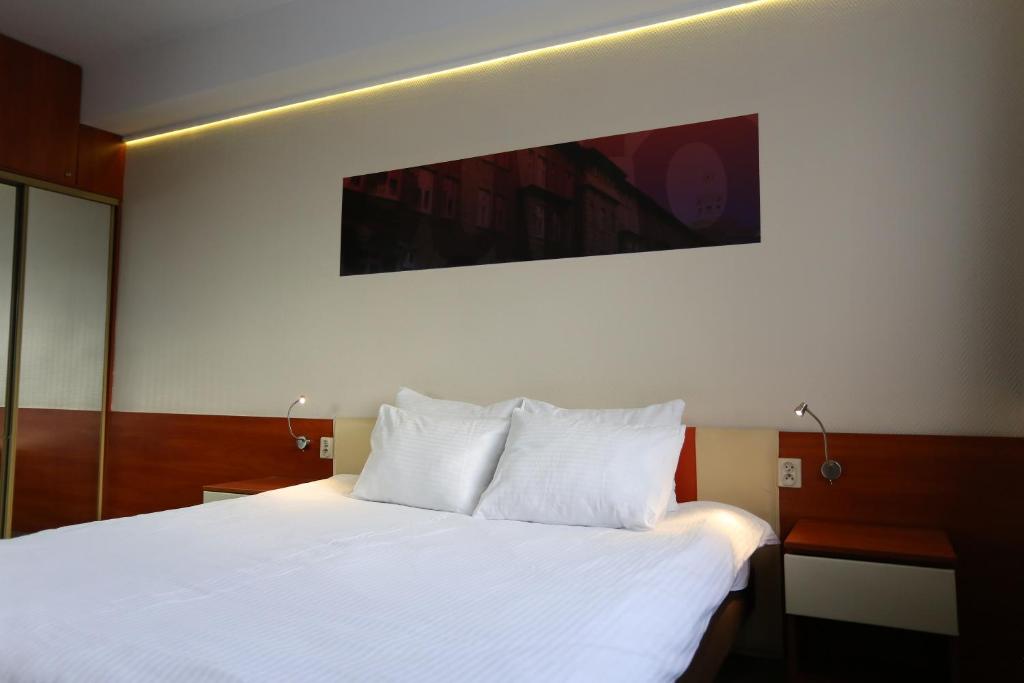 1 dormitorio con 1 cama grande con sábanas blancas en euroHOTEL Katowice Nikiszowiec, en Katowice