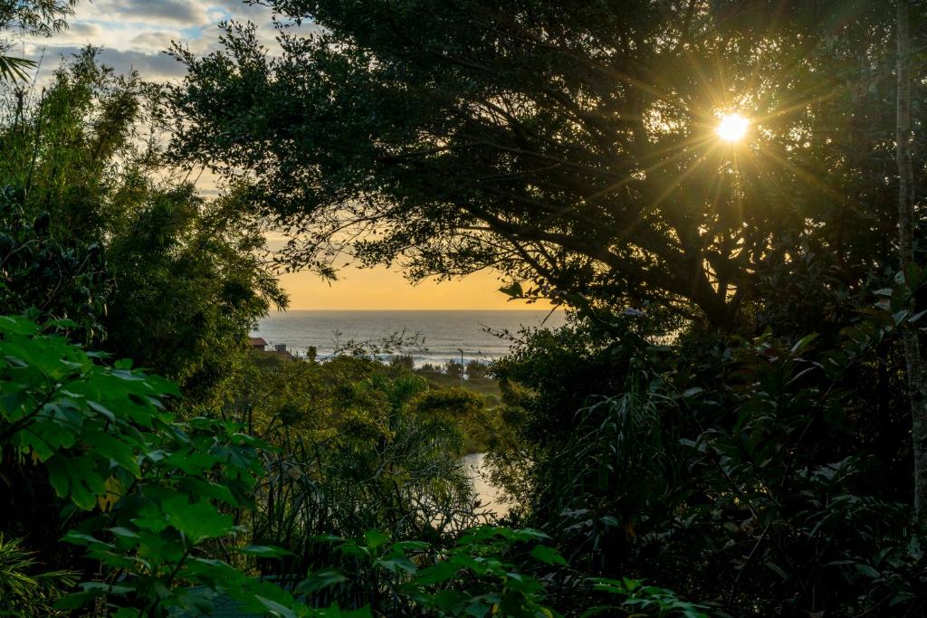 uma vista para o oceano a partir de uma praia com o pôr-do-sol em Coração da Terra Praia do Rosa na Praia do Rosa