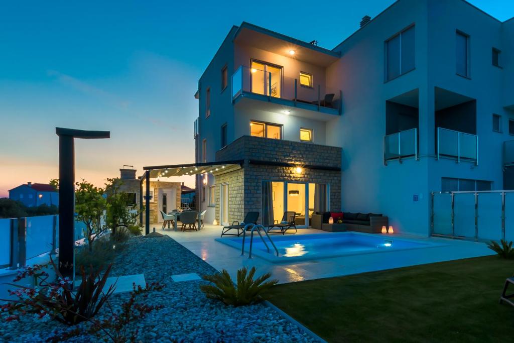 a villa with a swimming pool at dusk at Villa Buzuk in Vodice