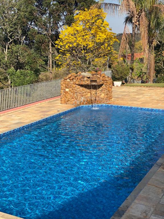 a swimming pool with a fountain in a yard at Chácara Cantinho que Deus me Deu in São Paulo