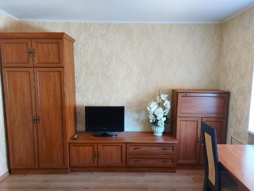 a room with a desk with a television and a vase of flowers at Dzīvoklis in Ventspils