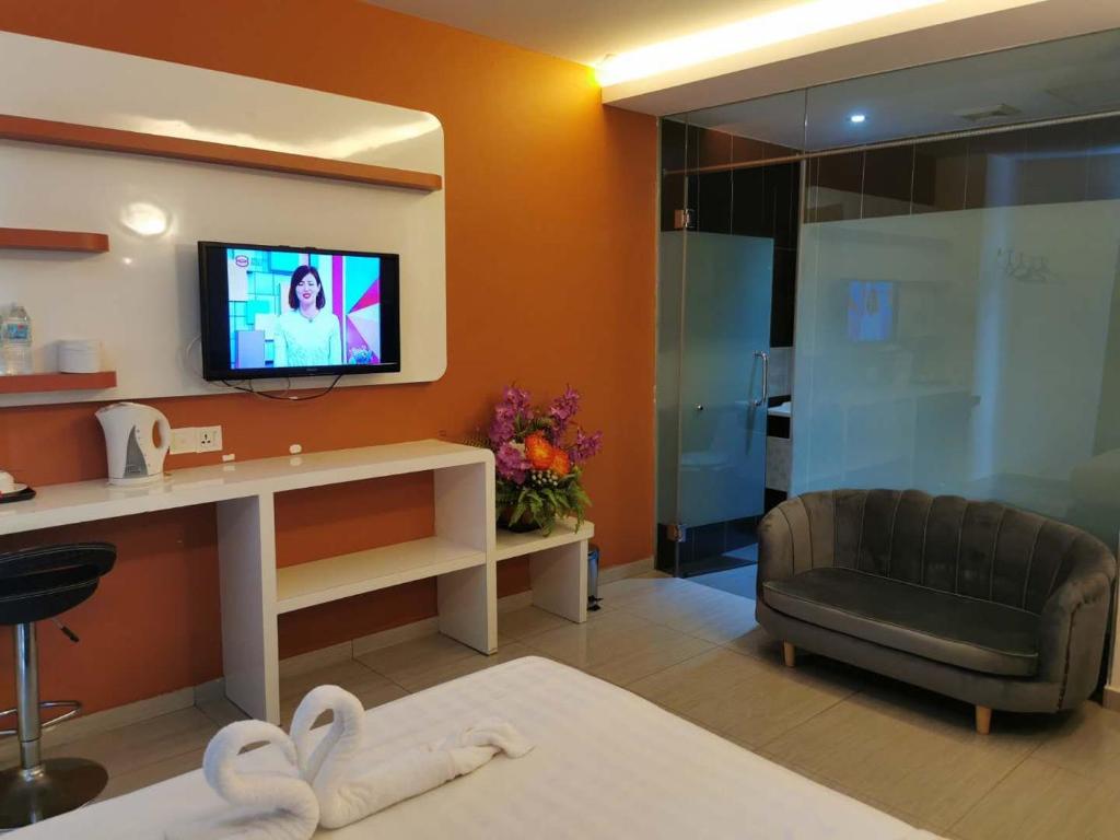 een woonkamer met een tv en een bank in een kamer bij Dolphin Hotel in Klang