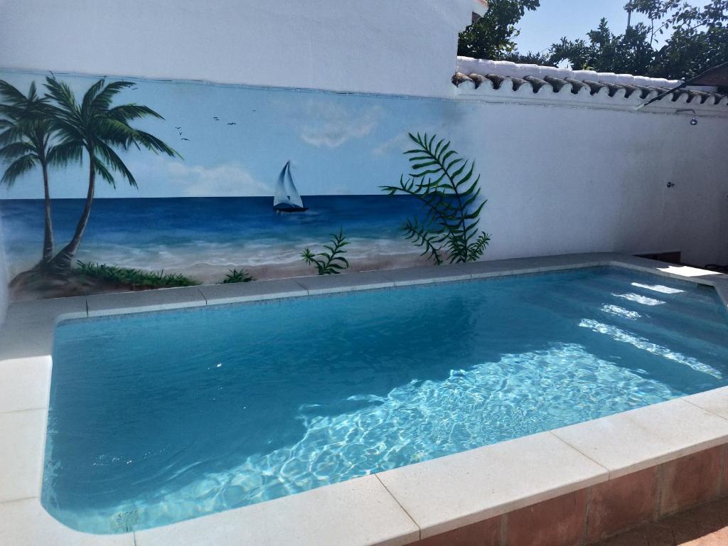 een zwembad met een muurschildering van een strand bij Casa en pueblo con piscina cerca de Córdoba in Encinarejo De Córdoba
