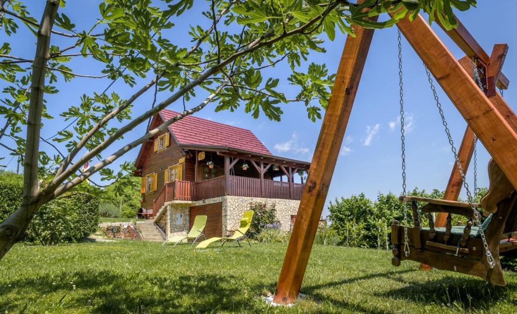 a swing in front of a house at Vita Natura with sauna and jacuzzi in Pihovec