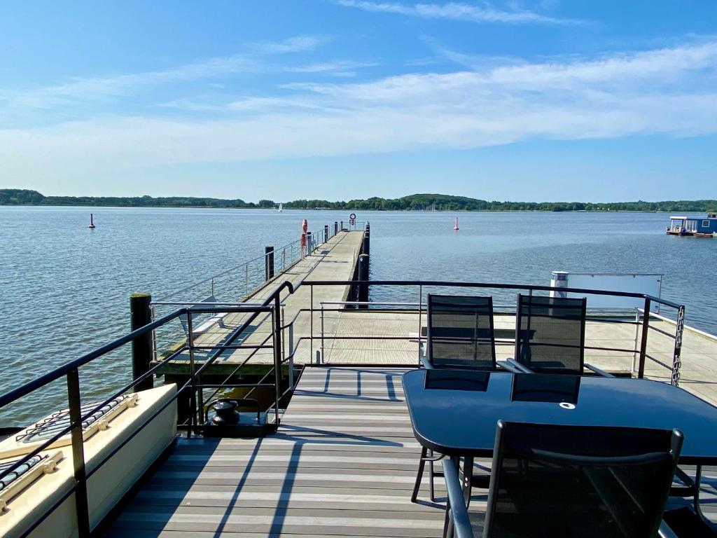 un muelle con 2 sillas y un barco en el agua en Island-dreams Hausboote Groth & Rhin, en Schleswig