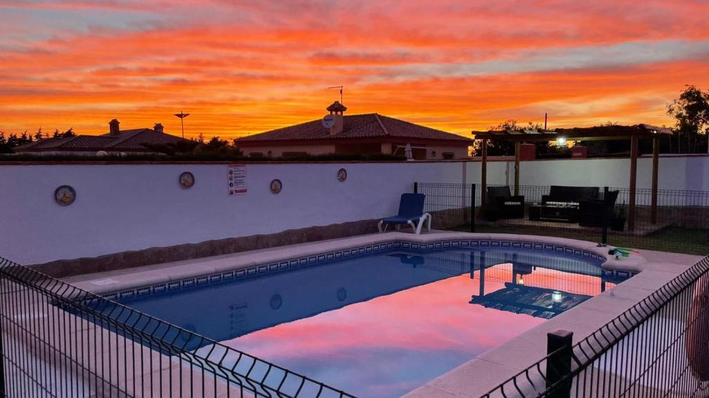 una piscina con puesta de sol en el fondo en casa lucia, en Cádiz