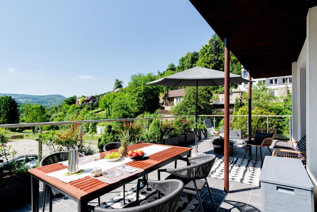 a patio with a table and chairs and an umbrella at Apartamenty Kozubnik - Apartament 16 z dużym tarasem in Porąbka