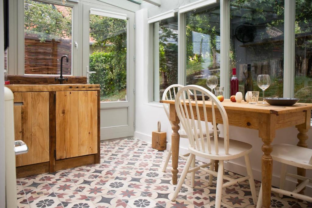 uma cozinha com mesa, cadeiras e janelas em Vinonima Vendégház em Hegymagas