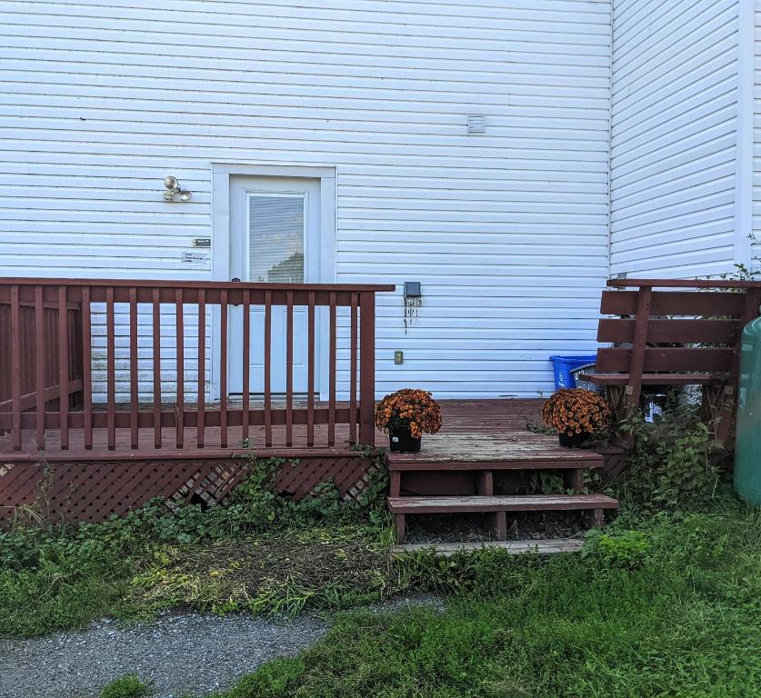 una terraza de madera con 2 bancos junto a una casa en Private 2 bedroom apartment, en Collins Bay
