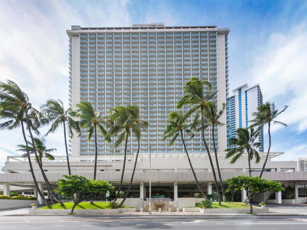 um edifício alto com palmeiras em frente em Ala Moana Condo by Orgoto em Honolulu