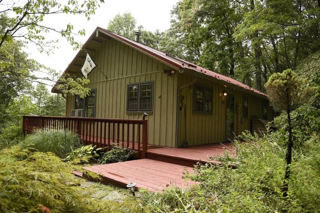 een klein groen huis met een houten terras bij Fox Trot Cabin in Meadows of Dan