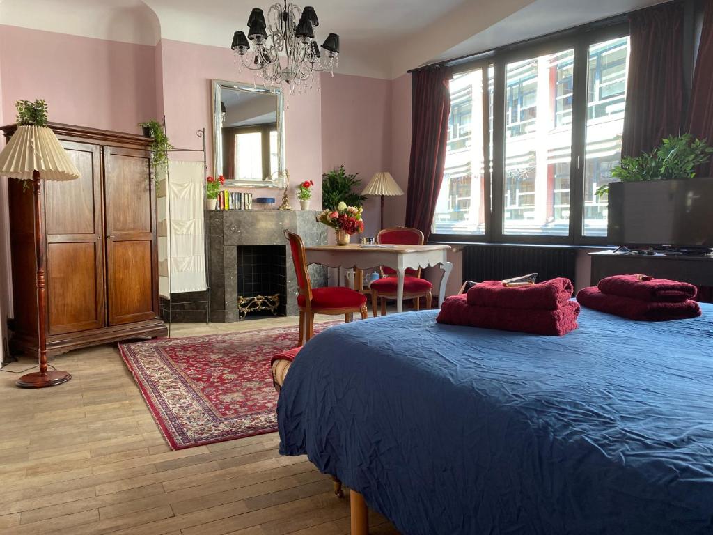 a bedroom with two beds and a table and a fireplace at The Pink Studio - Exceptional location IN city center - Unique & Elegant in Namur