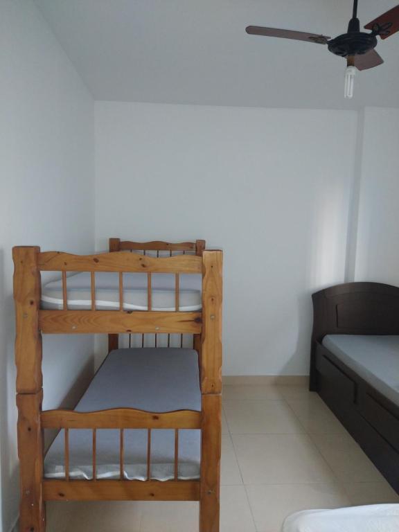 a bunk bed in a room with a ceiling fan at Apartamento Boqueirao in Praia Grande