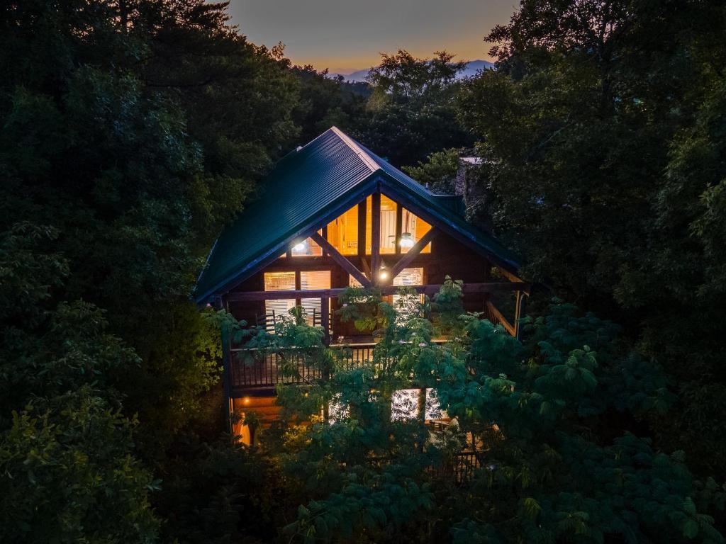 a house in the middle of a forest at night at Cozy log cabin!! In heart of PF & close to the Smokies in Pigeon Forge