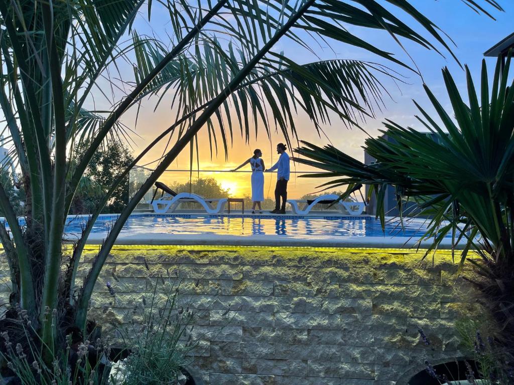 duas pessoas à beira de uma piscina ao pôr-do-sol em AM Palace em Ulcinj