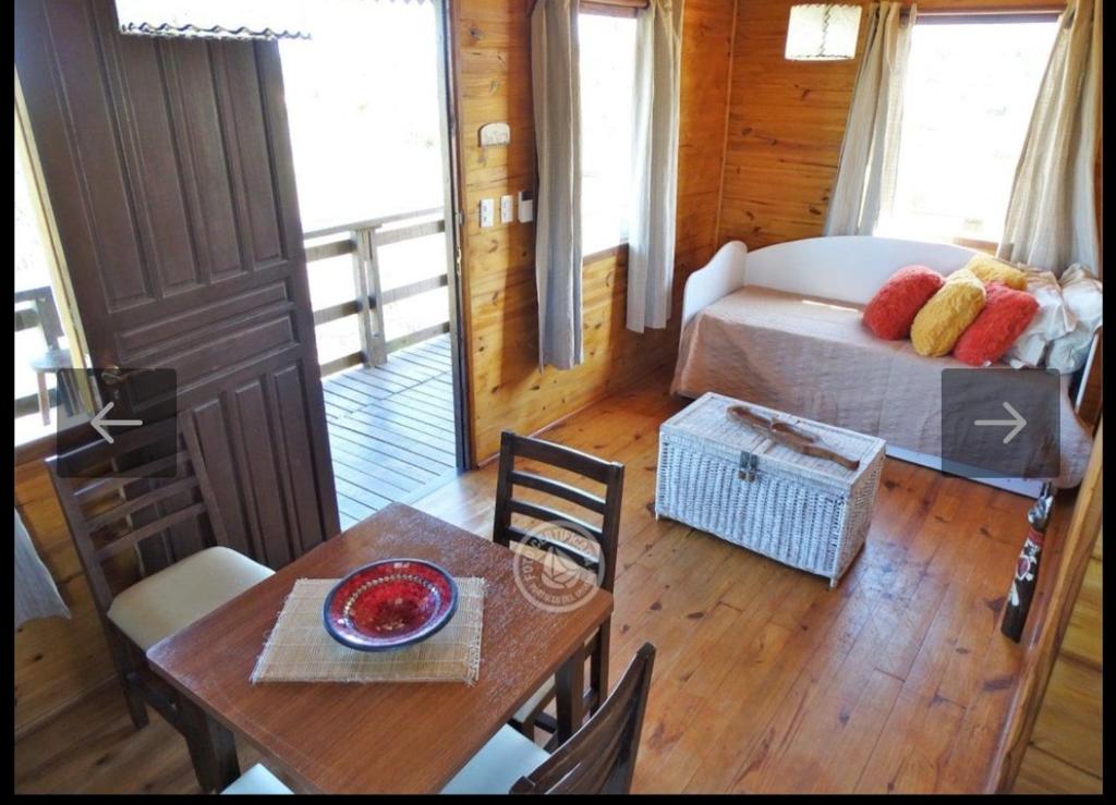 Habitación con cama, mesa, mesa y sillas. en Fama, en Punta del Diablo
