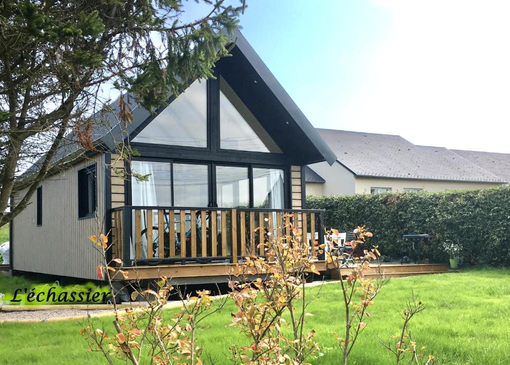 une petite maison avec une grande terrasse dans une cour dans l'établissement L'échassier, à Grandcamp-Maisy