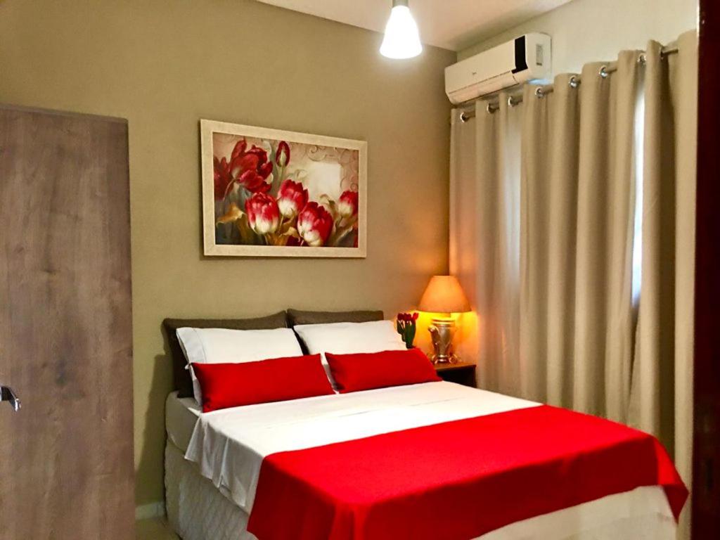 a bedroom with a bed with red and white sheets at Vila Sinhá in Bonito