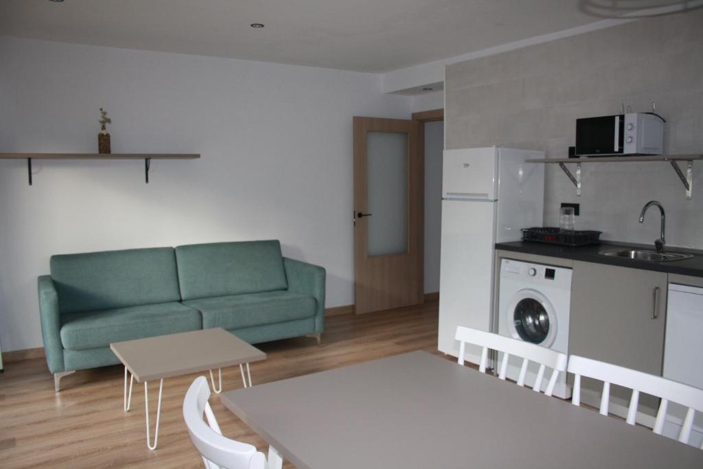 a living room with a green couch and a kitchen at Apt Nuevos con caballos Fio de Neu Laspaules in Laspaúles