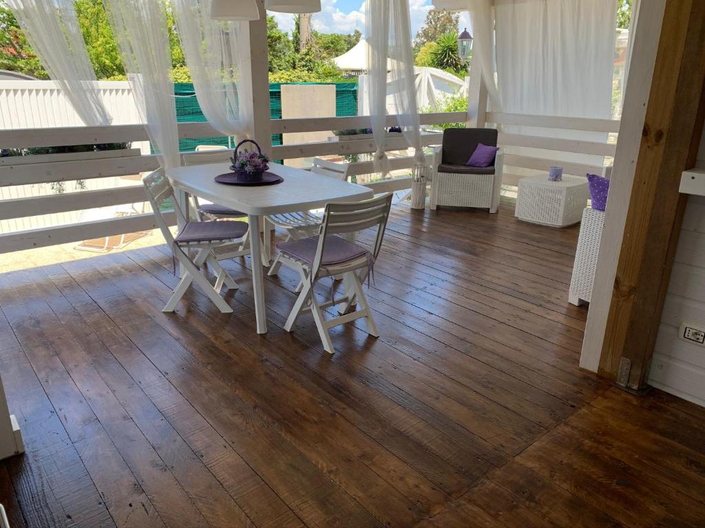 una mesa blanca y sillas en el suelo de madera en Appartamento Cottage Lilla a 150 mt dal mare en Borgo Sabotino