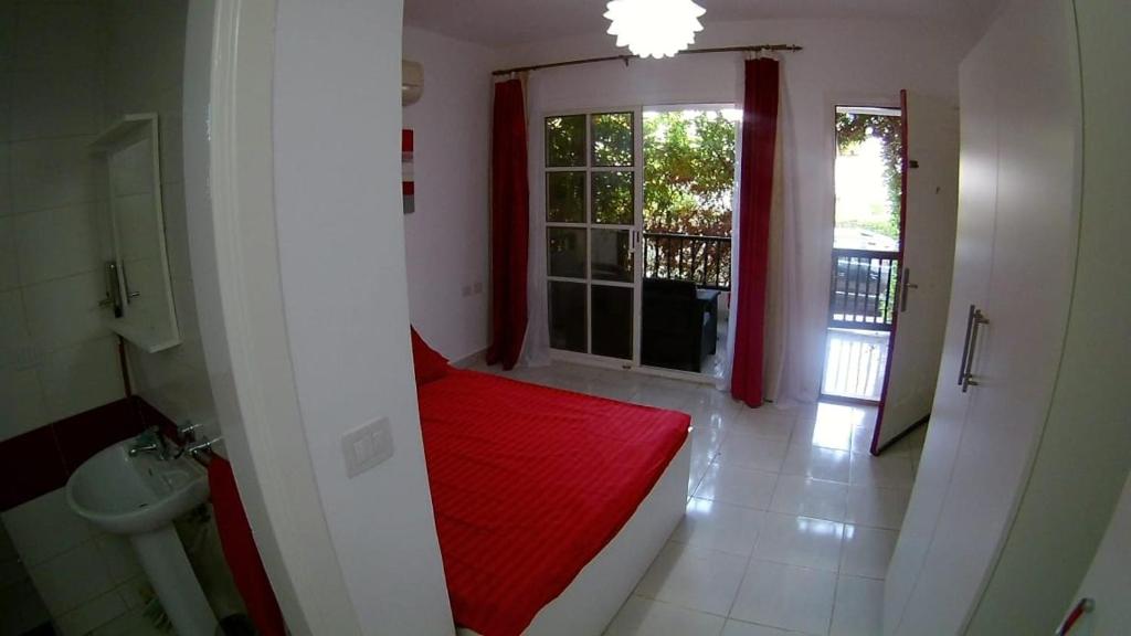 um quarto com uma cama vermelha numa casa de banho com uma janela em Delta Sharm Holiday em Sharm el Sheikh
