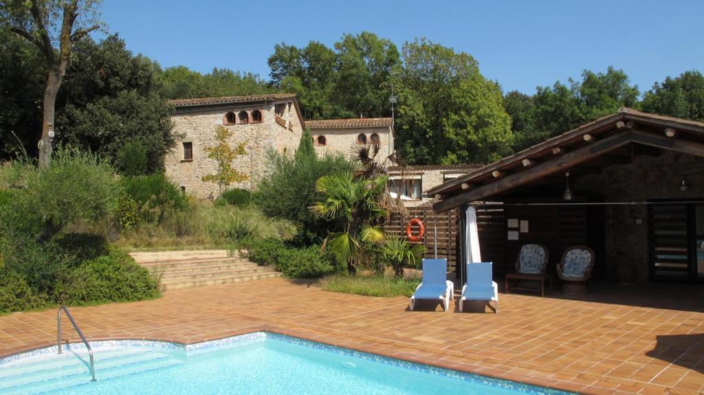 a patio with two blue chairs and a swimming pool at Can Vila in Sant Julià del Llor